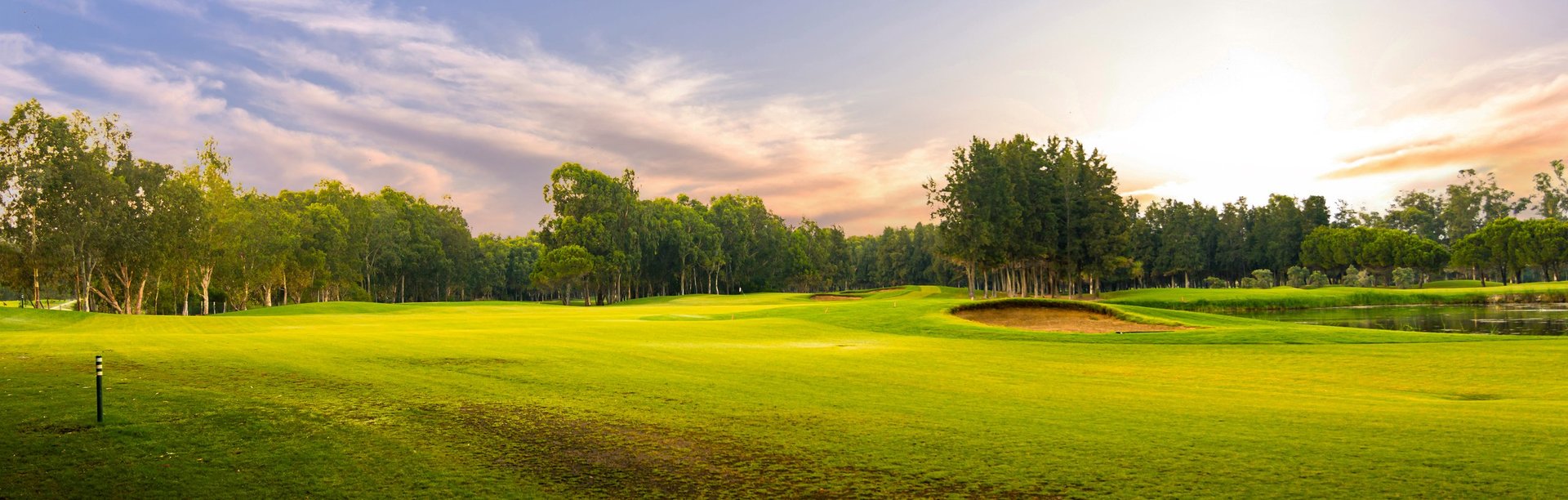 A scenic golf course with lush green fairways and trees, bathed in the soft light of sunrise