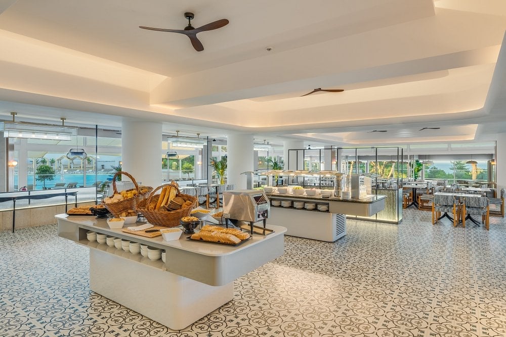 Modern lobby with golden sculptural art on display platforms, floor-to-ceiling windows, and ceiling fan in bright contemporary interior