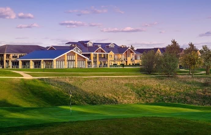 Luxury estate with yellow stone and blue roof overlooking a manicured golf course at sunset