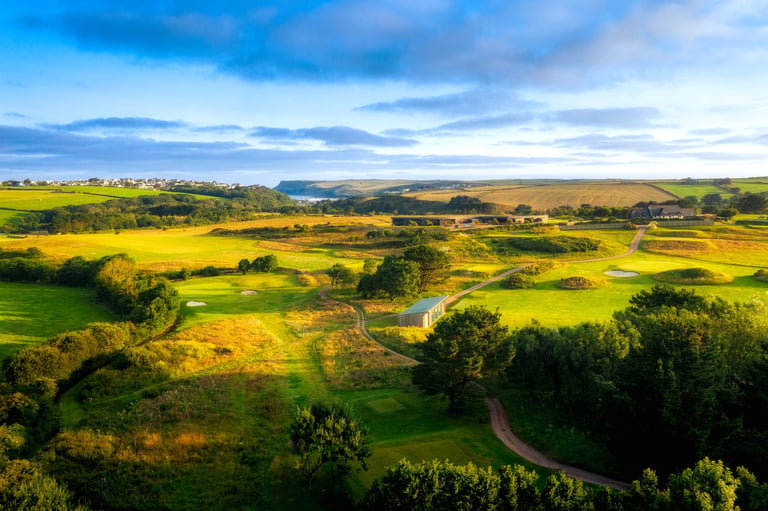 Aerial view of rolling countryside with patchwork of green and yellow fields under blue sky
