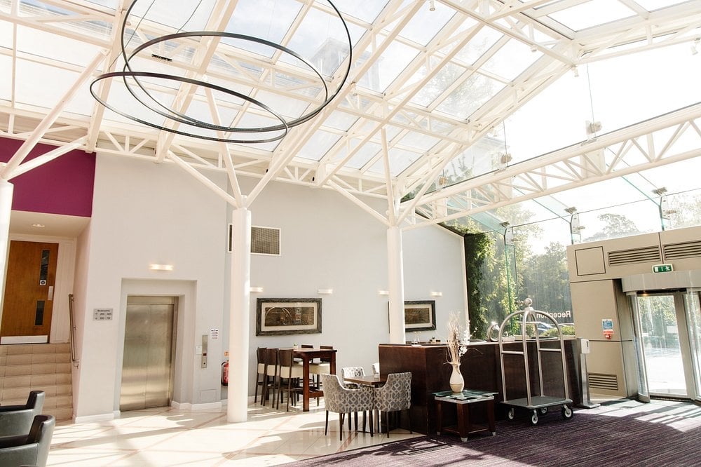 Modern art gallery interior with high glass ceiling, white walls, modern lighting fixture, and wooden furniture on display